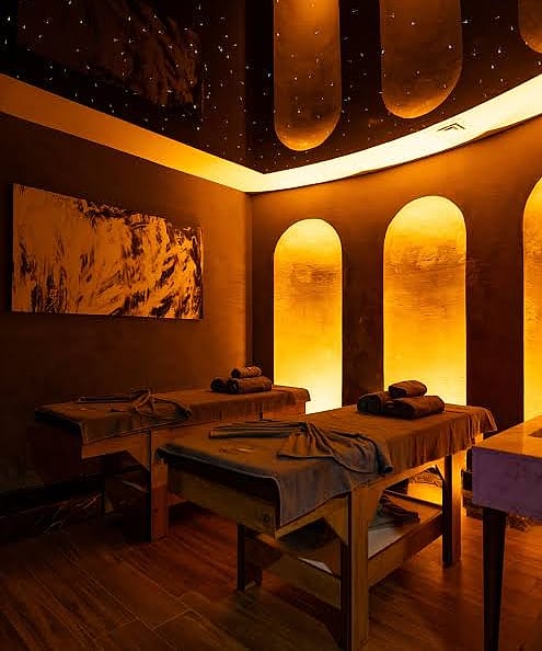 Private spa suite with two massage tables and glowing amber niches under a starlit ceiling